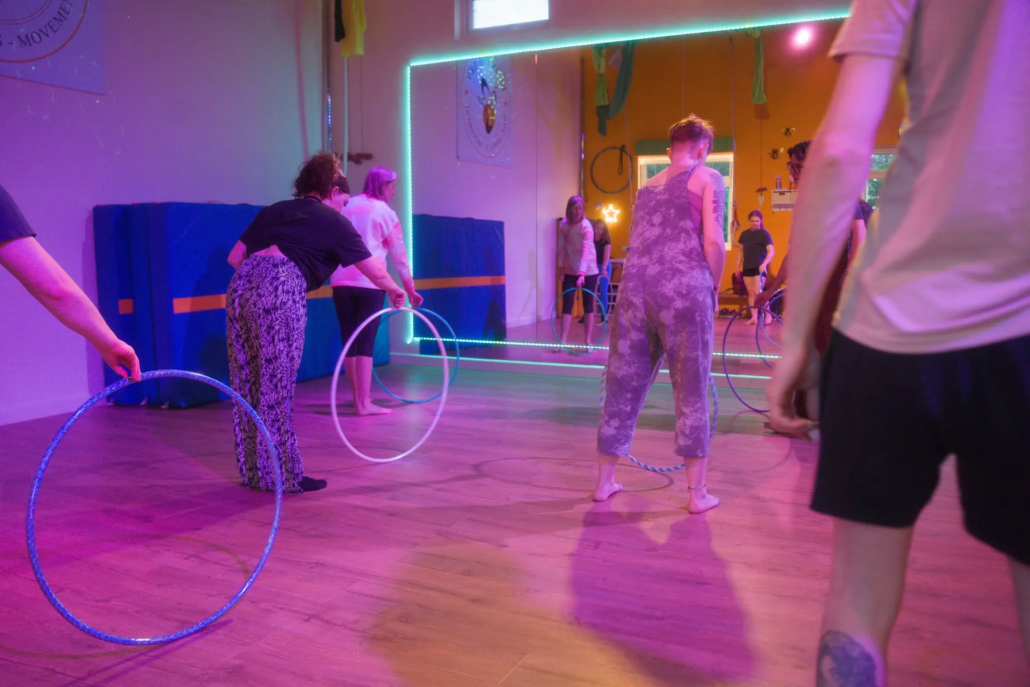 Flowsha workshop group passing and spinning hoops together under LED lights