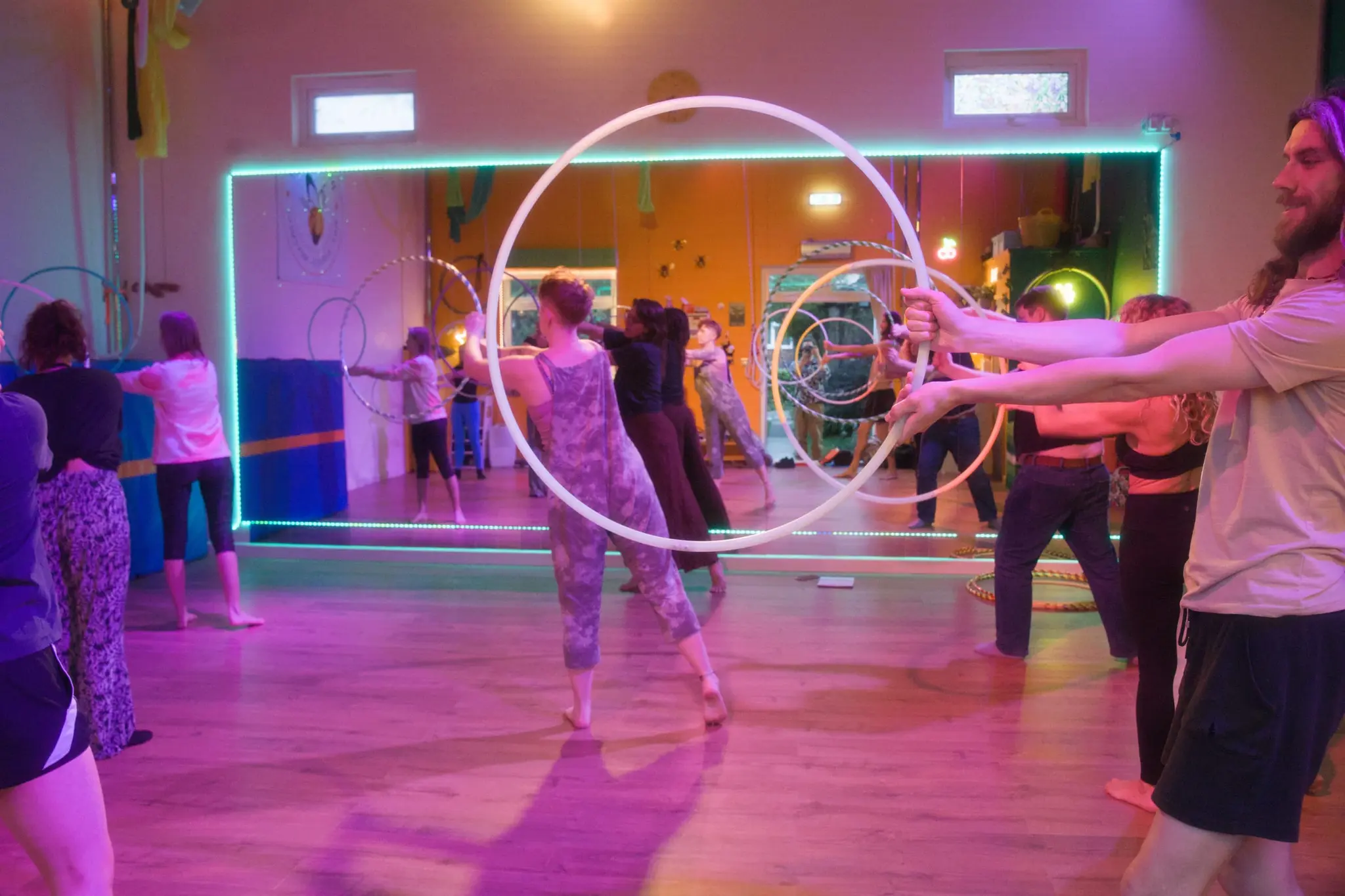 Osha of Flowsha spinning hoops in a colourfully lit studio