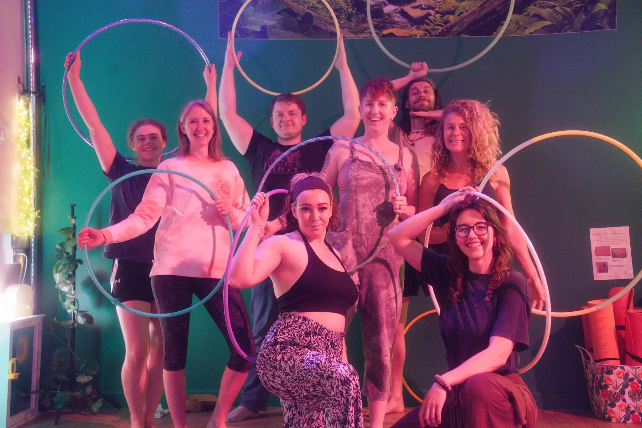 Smiling group of hoopers gathered with their colourful hoops after a class